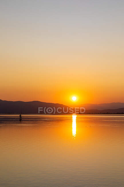 Cores intensas de um pôr do sol com reflexos na água — Fotografia de Stock