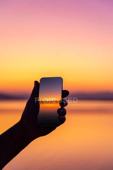 Силует чоловіка, який робить фотографію заходу сонця зі своїм мобільним — стокове фото