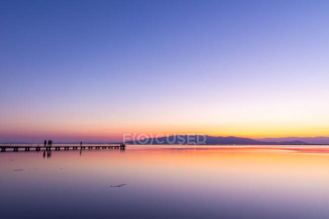 Turisti anonimi sul molo durante il tramonto — Foto stock