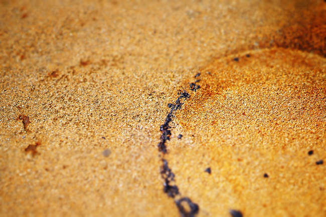 Fermeture de la surface sableuse avec empreinte ronde et gouttes foncées — Photo de stock