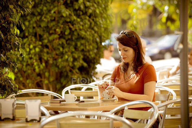 Casual senhora relaxada desfrutando de uma xícara de chá enquanto sentado no acolhedor terraço do café de verão e almoçando — Fotografia de Stock