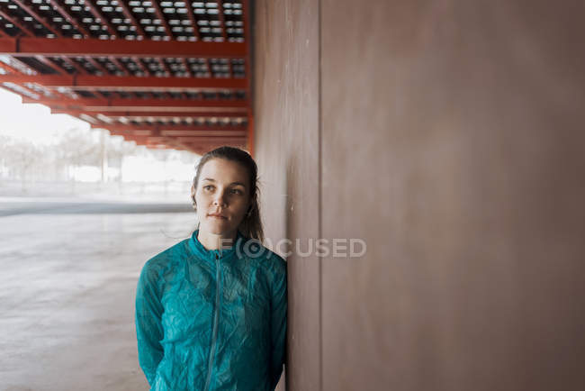 Portrait of confident female athlete leaning against brick wall — Stock Photo