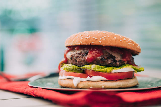 Köstliche hausgemachte Rindfleisch-Burger mit Salat, Tomaten und Sauce auf grünem Teller. — Stockfoto