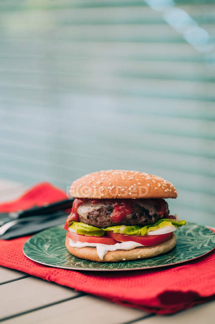 Delizioso hamburger di manzo fatto in casa con lattuga, pomodoro e salsa sul piatto verde . — Foto stock