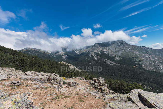 Paisagem surpreendente de colinas de pedra cobertas por grama seca sob grandes nuvens brancas fofas no céu — Fotografia de Stock