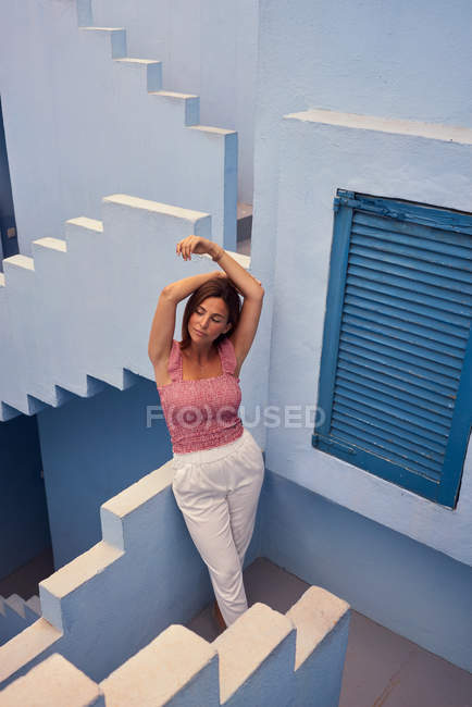 Dall'alto vista di giovane donna che cammina al piano di sopra del moderno edificio blu e occhi chiusi — Foto stock