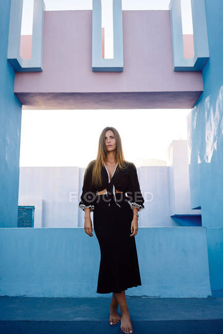 Woman standing on modern blue building and looking away — Stock Photo