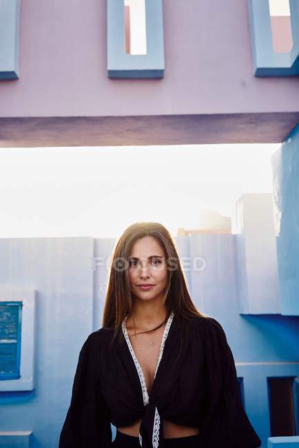 Donna in piedi su un moderno edificio blu e guardando la fotocamera — Foto stock