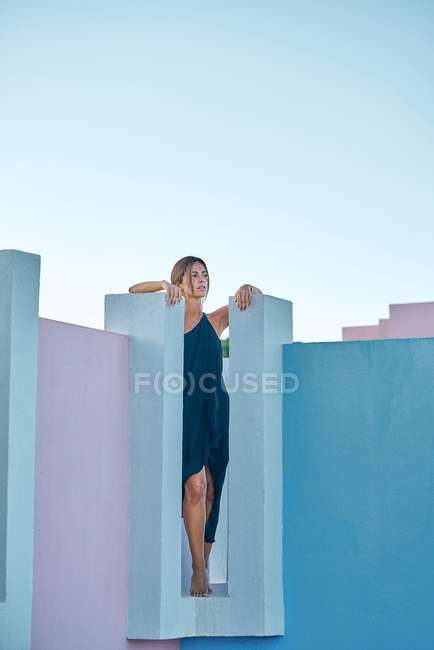 Femme debout sur le dessus du bâtiment bleu et regardant loin — Photo de stock