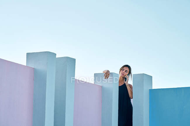 Женщина, стоящая на вершине синего здания и разговаривающая по смартфону — стоковое фото