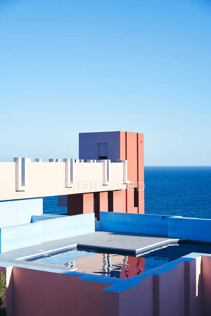 Incredibile piscina con acqua dolce che riflette il cielo sul tetto di interessante edificio a forma di giornata di sole luminoso — Foto stock