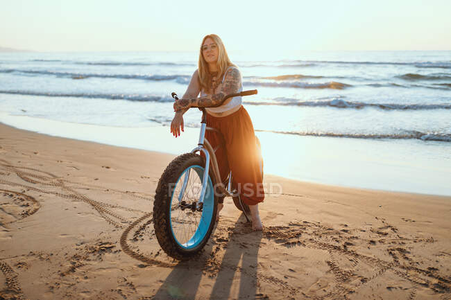 Mujer alegre montar en bicicleta a lo largo de la playa tranquila - foto de stock
