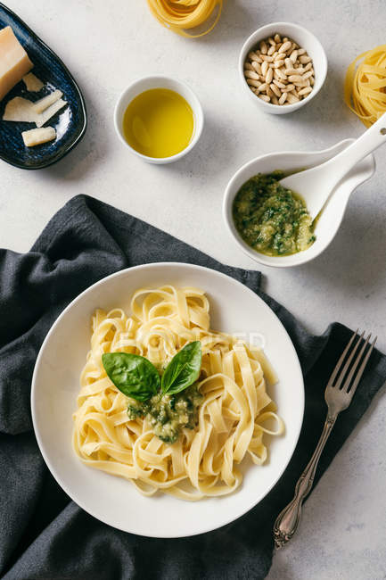 Served plate of pesto pasta next to bowl of sauce on table — Stock Photo