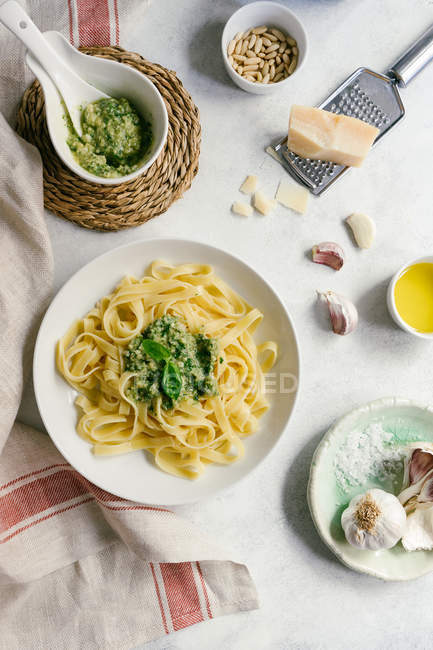 Platón servido de pasta de pesto junto al bol de salsa sobre la mesa. - foto de stock