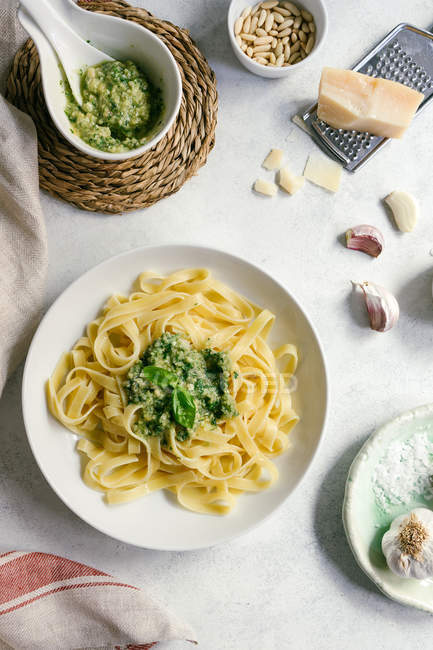 Servierteller mit Pesto-Pasta neben Schüssel mit Sauce auf dem Tisch — Stockfoto