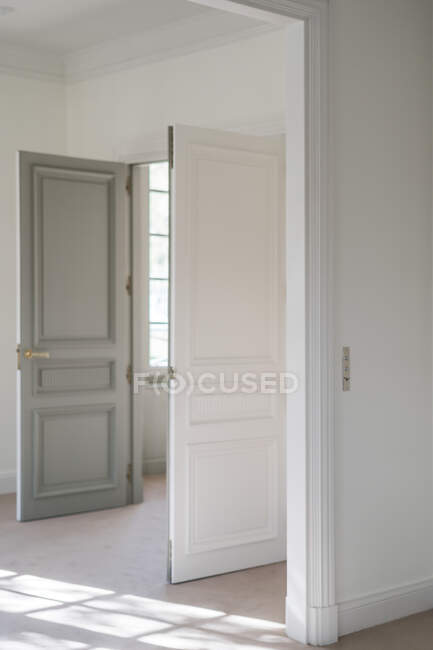 Открытая двуцветная качающаяся дверь с современной ручкой в белом минималистичном интерьере — стоковое фото