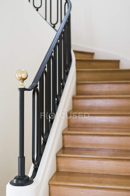 Escadaria de madeira maciça com grade preta em casa com interior leve — Fotografia de Stock