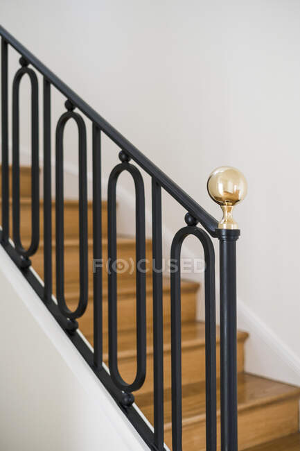 Цельная деревянная лестница с черными перилами в доме с легким интерьером — стоковое фото