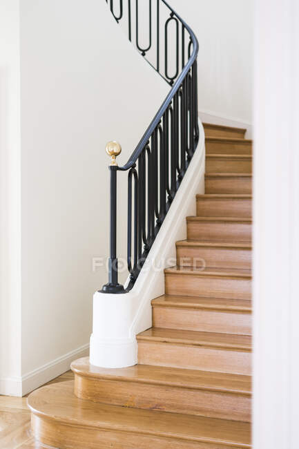 Solid wooden staircase with black railing in house with light interior — Stock Photo