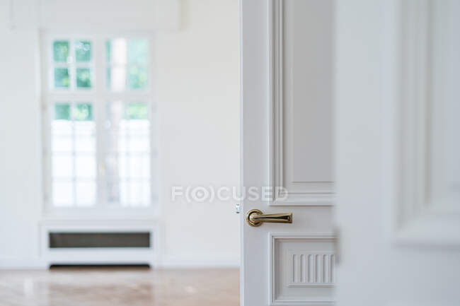 Offene weiße Tür mit goldenem Griff in leicht minimalistischem Interieur auf unscharfem Hintergrund — Stockfoto