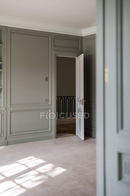 Интерьер светлого дома с панельной стеной и белой открытой дверью с лестницей в минималистском дизайне — стоковое фото