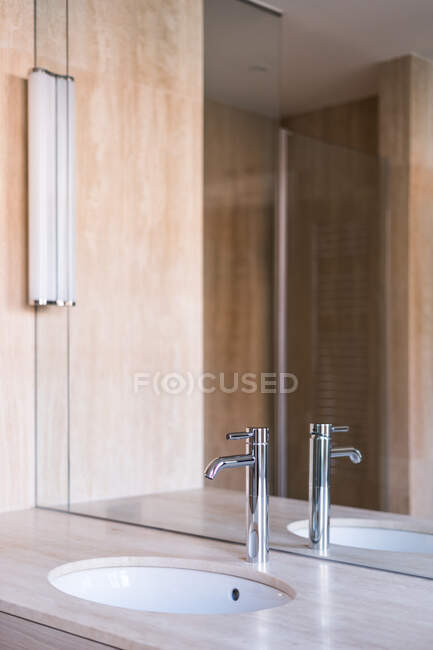Овальний басейн і блискучий сталевий кран на дерев'яній підставці з дзеркалом у сучасній ванній кімнаті. — стокове фото