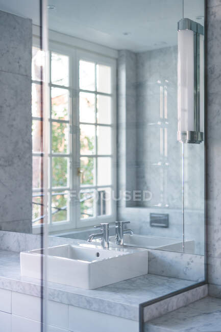 Square white washbasin and steel faucet in chic bathroom in daylight - foto de stock