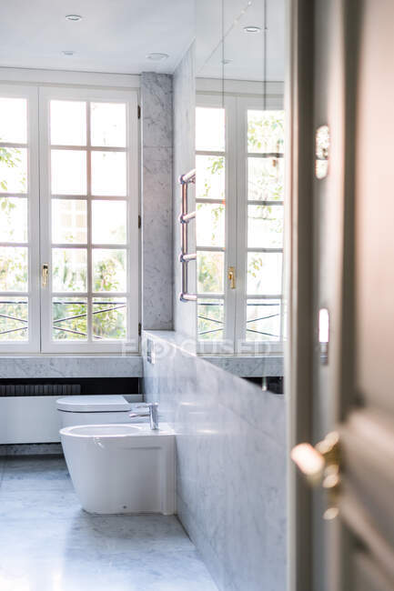 Bidet et toilettes dans la salle de bain minimaliste lumière décorée avec des carreaux de marbre et des miroirs sur le mur — Photo de stock