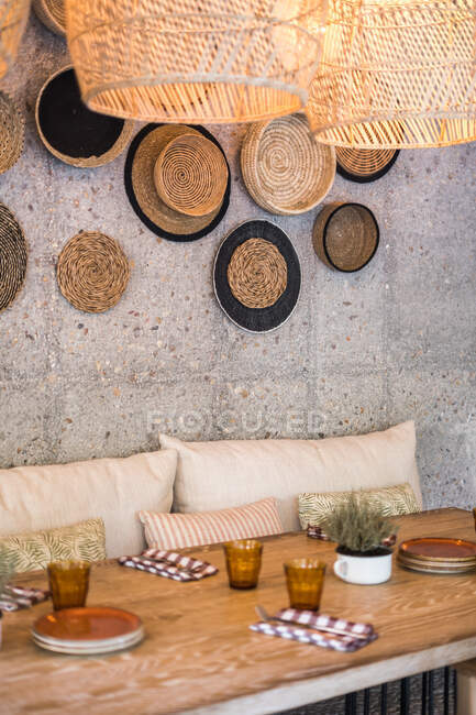 Authentic wicker lampshades with warm light hanging over served table in empty outside restaurant - foto de stock