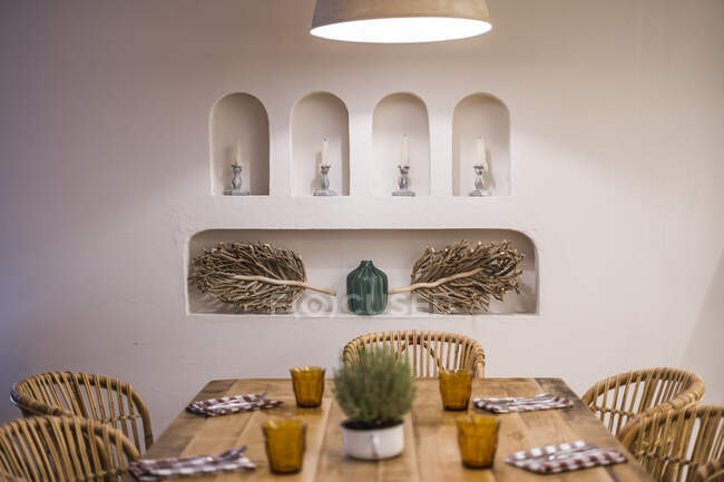 Classic lampshades with warm light hanging over set wooden table in light hall - foto de stock