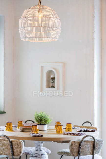 Classic lampshades with warm light hanging over set wooden table in light hall - foto de stock
