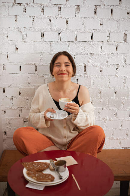 Friedliche Frau trinkt Kaffee, während sie sich zu Hause ausruht — Stockfoto