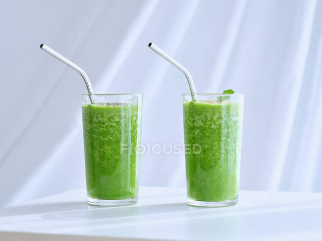 Bicchieri di frullato verde sul tavolo bianco — Foto stock