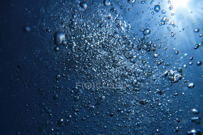 Haciendo estallar burbujas de aire en el agua de mar - foto de stock