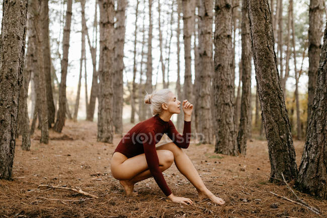 Hermosa mujer moderna descansando descalza en el bosque siempreverde - foto de stock