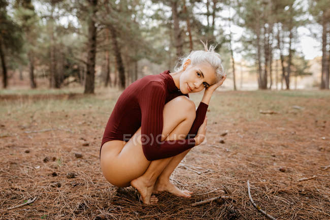 Beautiful modern woman resting barefoot in evergreen forest — Stock Photo