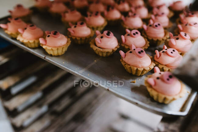 Bandeja de metal con sabrosa masa en forma de cerdo colocada en rack en panadería profesional - foto de stock