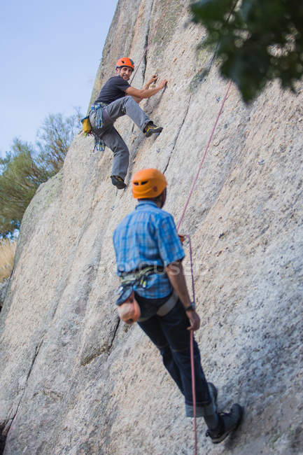 Aventuriers escalade montagne port harnais de sécurité contre paysage pittoresque — Photo de stock