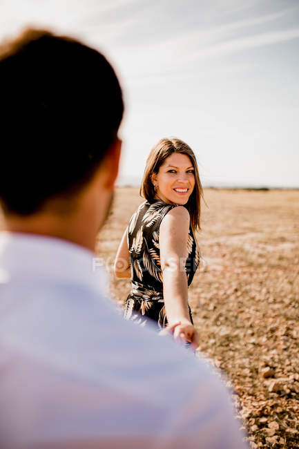 Soft focus of delighted tender couple holding hands on field in summer — Stock Photo