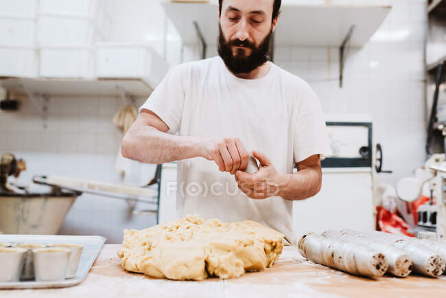 Chef putting fresh soft dough in small cup over table in bakery kitchen — Stock Photo