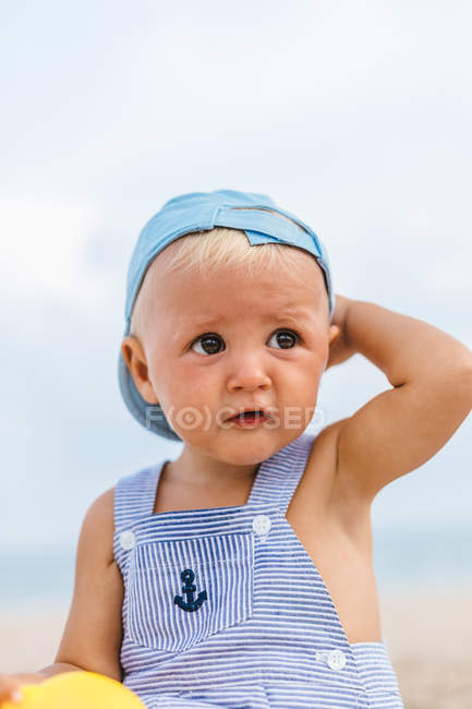 Retrato de un bebé rubio sonriendo en la playa - foto de stock