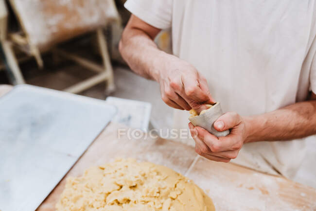De confeiteiro anônimo colocando massa macia fresca em pequena xícara sobre mesa na cozinha da padaria — Fotografia de Stock