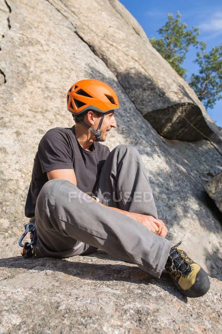 Rock climber is putting on his climbers shoes to start climbing — Stock Photo