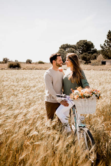 Sincere lovers posing by bicycle on rye field — Stock Photo