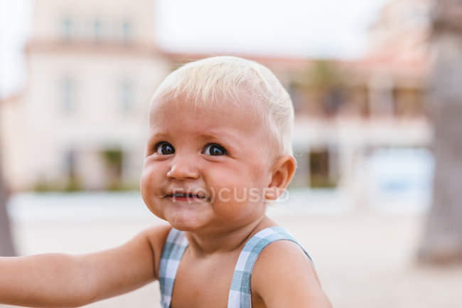 Retrato de un bebé rubio sonriendo en la playa - foto de stock