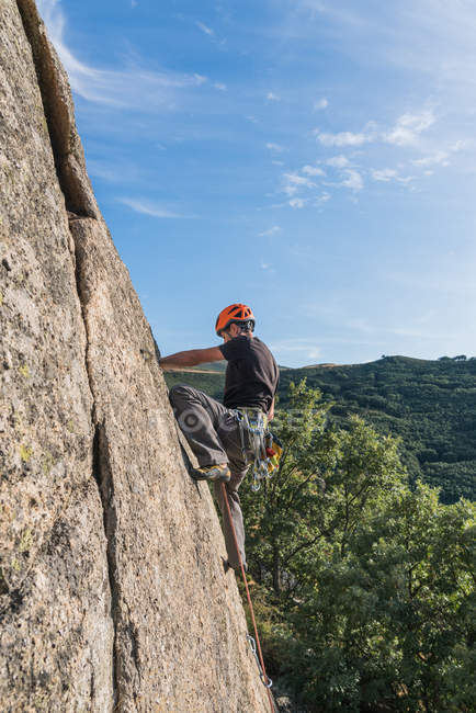 Mann klettert mit Kletterausrüstung auf Felsen in der Natur — Stockfoto