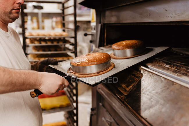 Man peeking inside professional oven while working in bakery — Stock Photo