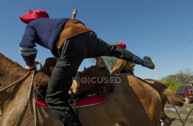 Vista trasera del jinete de caballo en traje cálido y la gorra saltando en caballo marrón en rancho - foto de stock