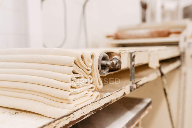 Schlaue Maschine rollt frischen, weichen Teig für die Teigzubereitung in der Küche einer professionellen Bäckerei — Stockfoto