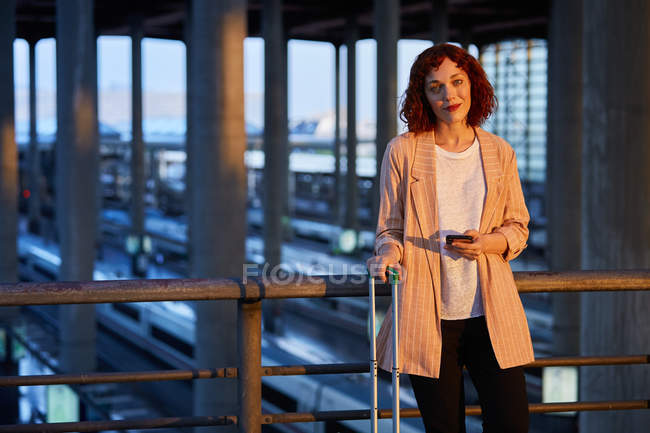 Smiling young woman holding phone at station — Stock Photo